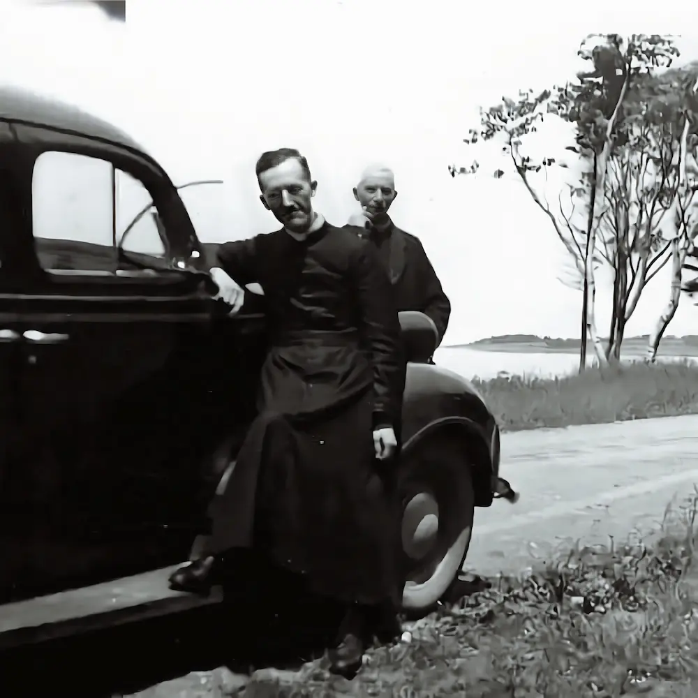 Le Père Basile Babin et un confrère près d’une automobile ancienne